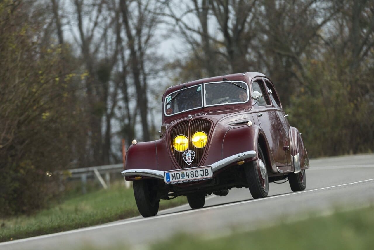 Vorkriegsautos schauen anders aus, niemand glaubt dem Peugeot 402 sein Alter. Luft­widerstand 0,68 ergibt Jahrzehnte später die Nachuntersuchung in einem windigen Kanal. Gelbes Licht ist seit 1936 der Franzosen Brauch, Brüsseler Harmonisierungs-Neurotiker stellen  das erst 1993 ab. Scheinwerferaugen hinterm Kühlergrill, gut geschützt gegen Steinschlag  und Wildtiere. Darunter das Pannenhilfeloch  zur Starterkurbel.